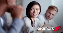 Group of professionals sitting and talking, Aramark logo in lower right corner