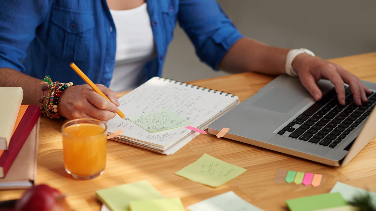 Professor planning with computer and sticky notes