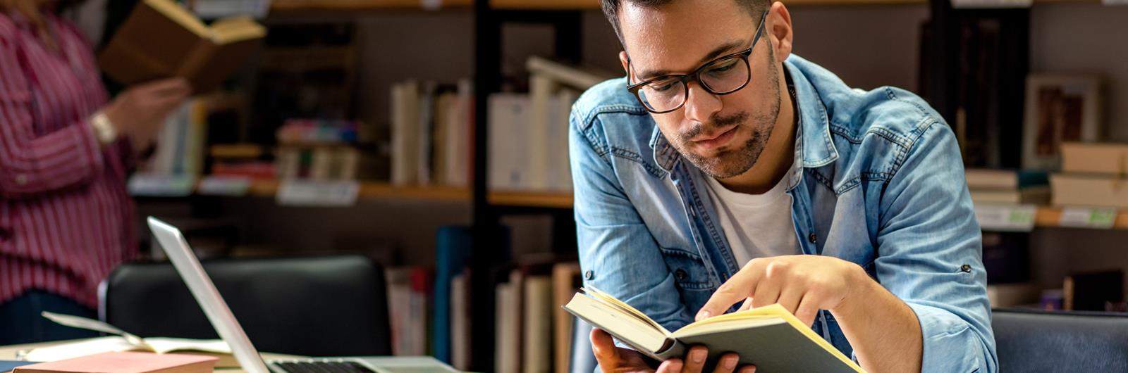 Young male student study in the library reading book.