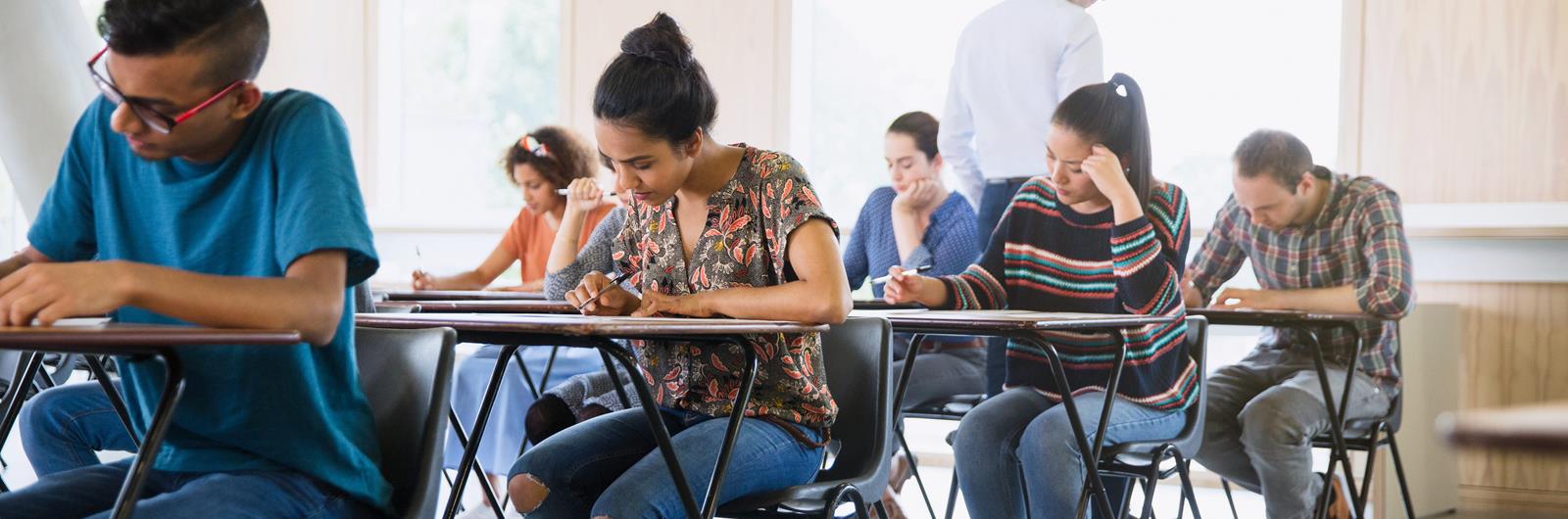Professor watching college students taking test in classroom.