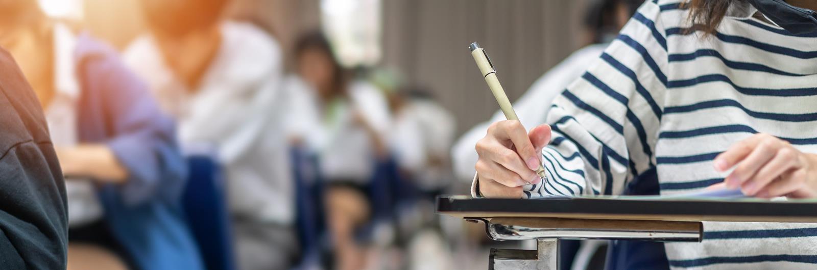 Exam at school with student's taking educational admission test in class, thinking hard, writing answer in university classroom, education and world literacy day concept.