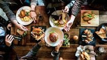 looking down on a table of diners passing plates full of fool