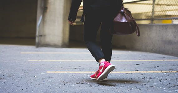 A woman wearing pink shoes walking through a parking garage