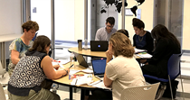 6 people working together around a desk 