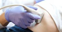 Close up of a gloved hand performing a liver scan