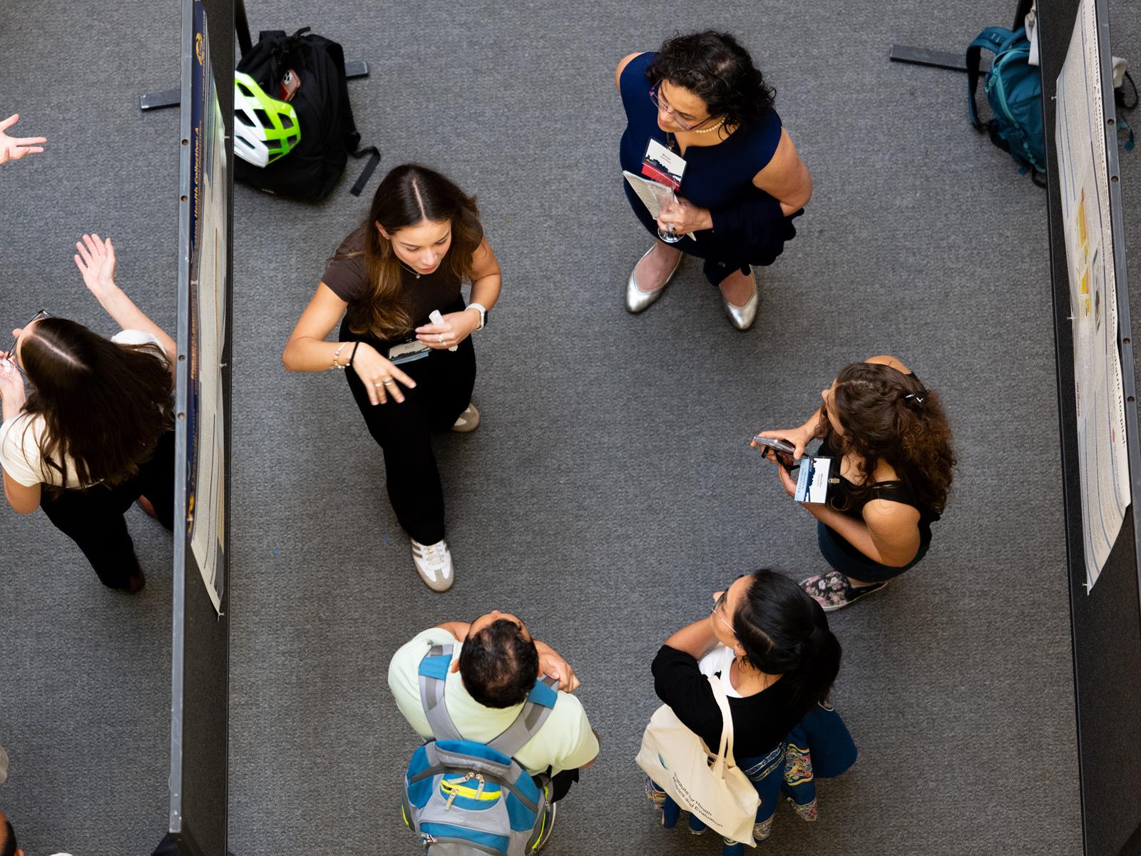 Overhead shot of researchers discussing their posters during UHC' 2025 Symposium 