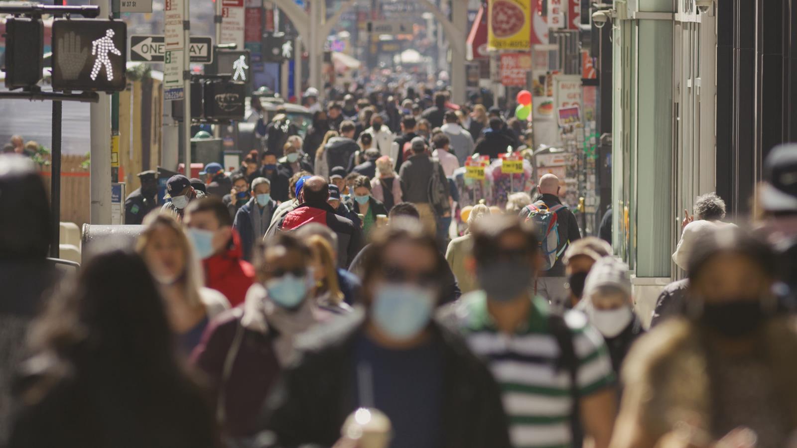 Anonymous crowd of people walking street wearing masks during Covid 19 pandemic in New York City