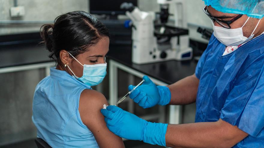 Healthcare worker administering a shot to woman wearing a mask