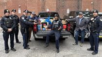 Drexel police officers standing by a black pick-up truck filled with presents.