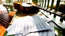 blank music sheets scattered next to an acoustic guitar