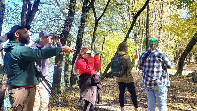 People standing out in a forest with camera crew and equipment