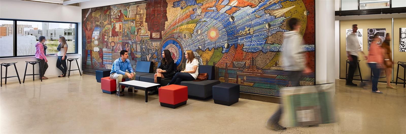 Students sitting in front of an indoor mural