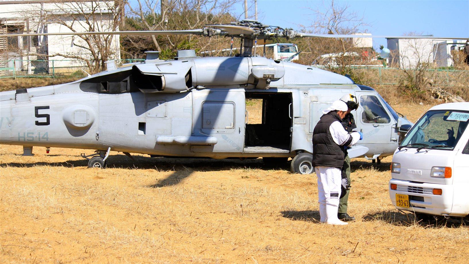 Two men talking in front of a military helicopter in Japan