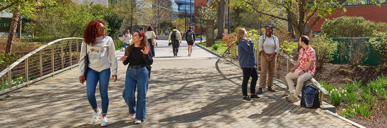 Drexel students talking and walking across bridge