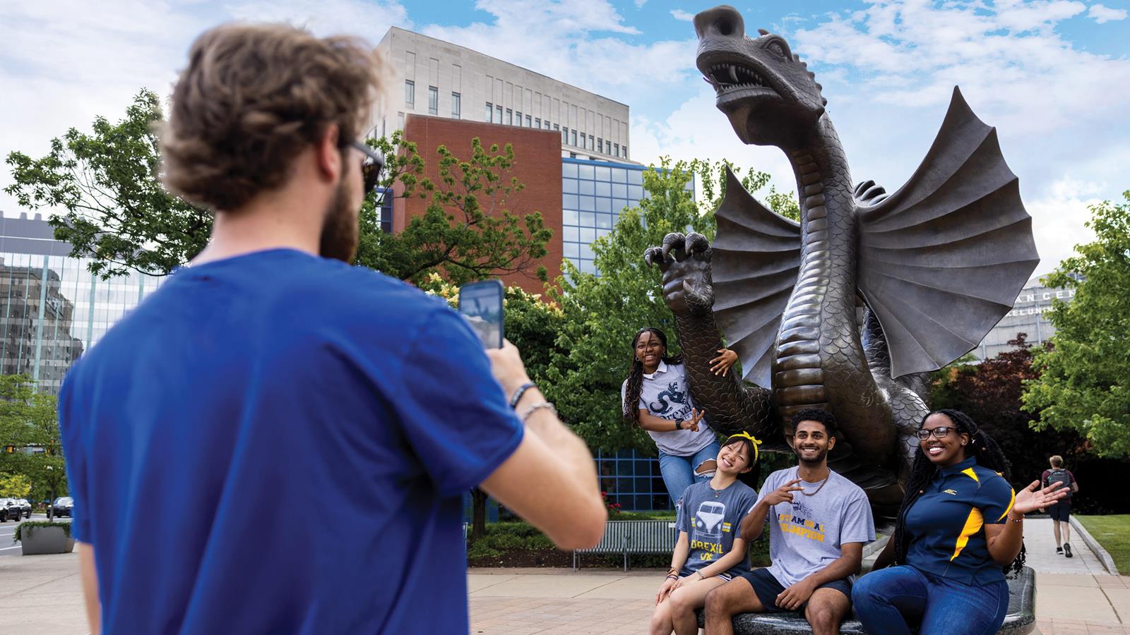 Students posing for a photo with the dragon statue on campus
