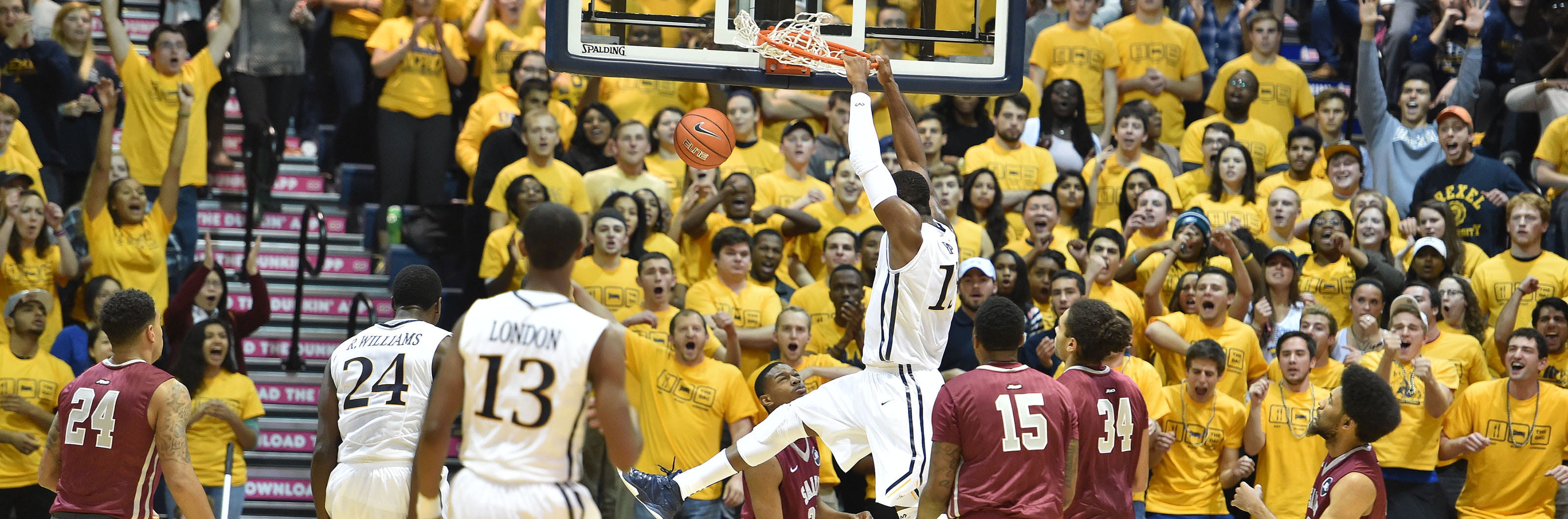 A member of Drexel's Men's basketball team slam dunking on the net 