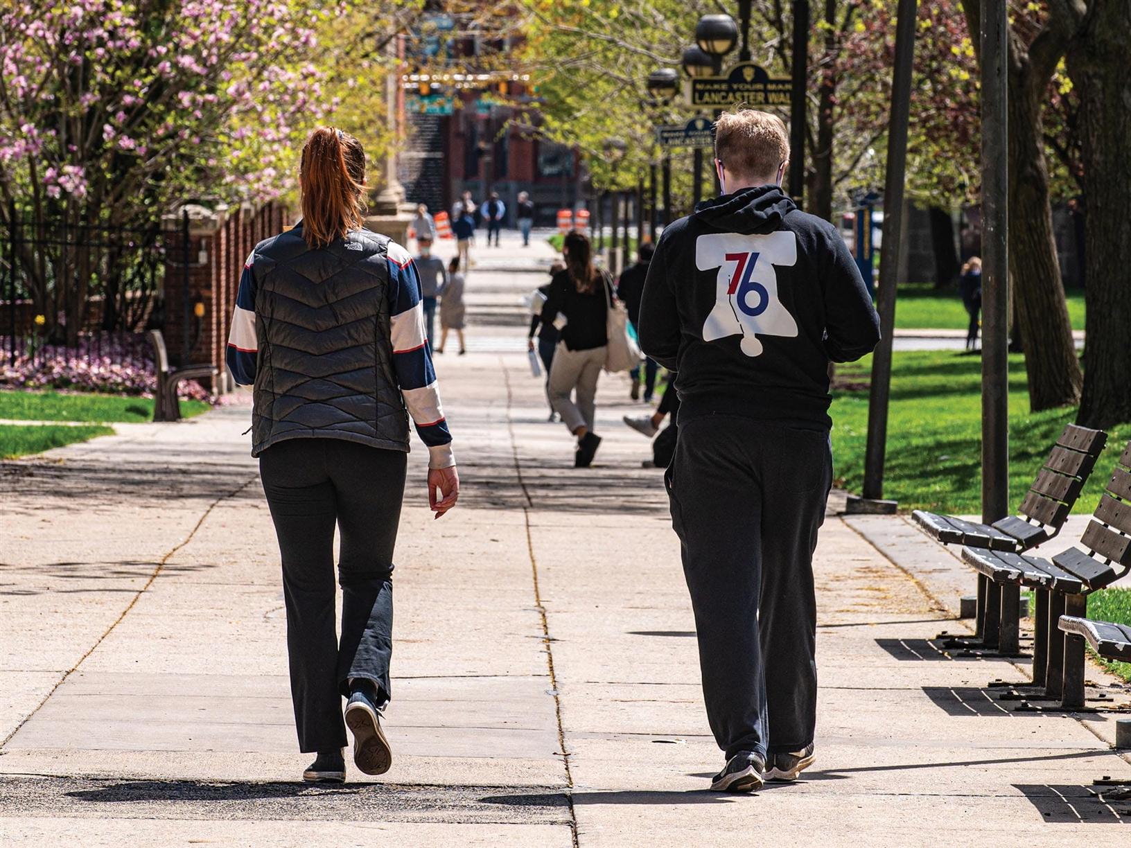 Two students safely enjoying a walk on campus.