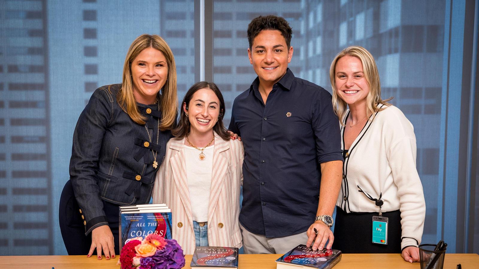 Four people huddled together for a photo in front of a book.