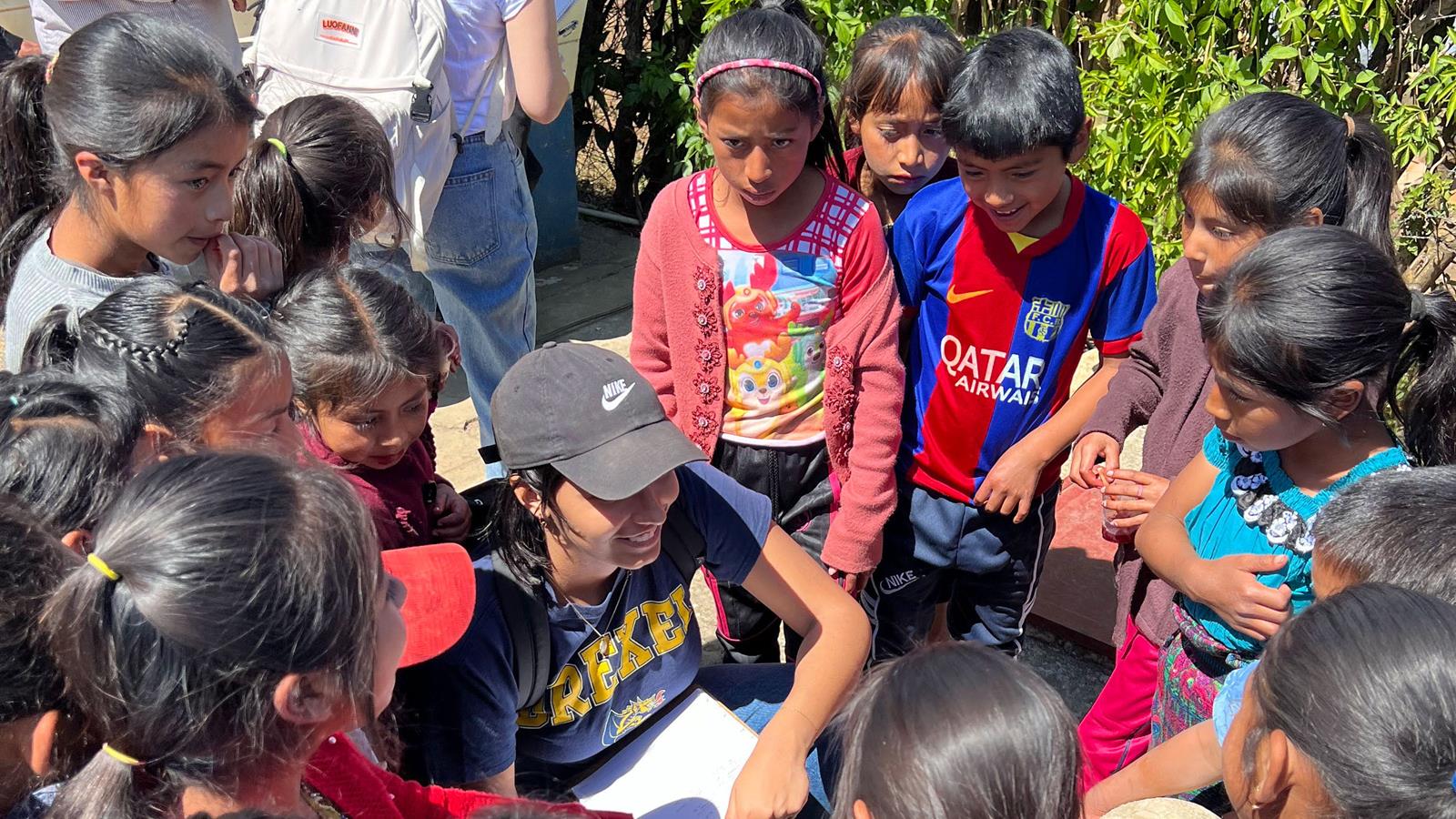 Children gathered around a Drexel student