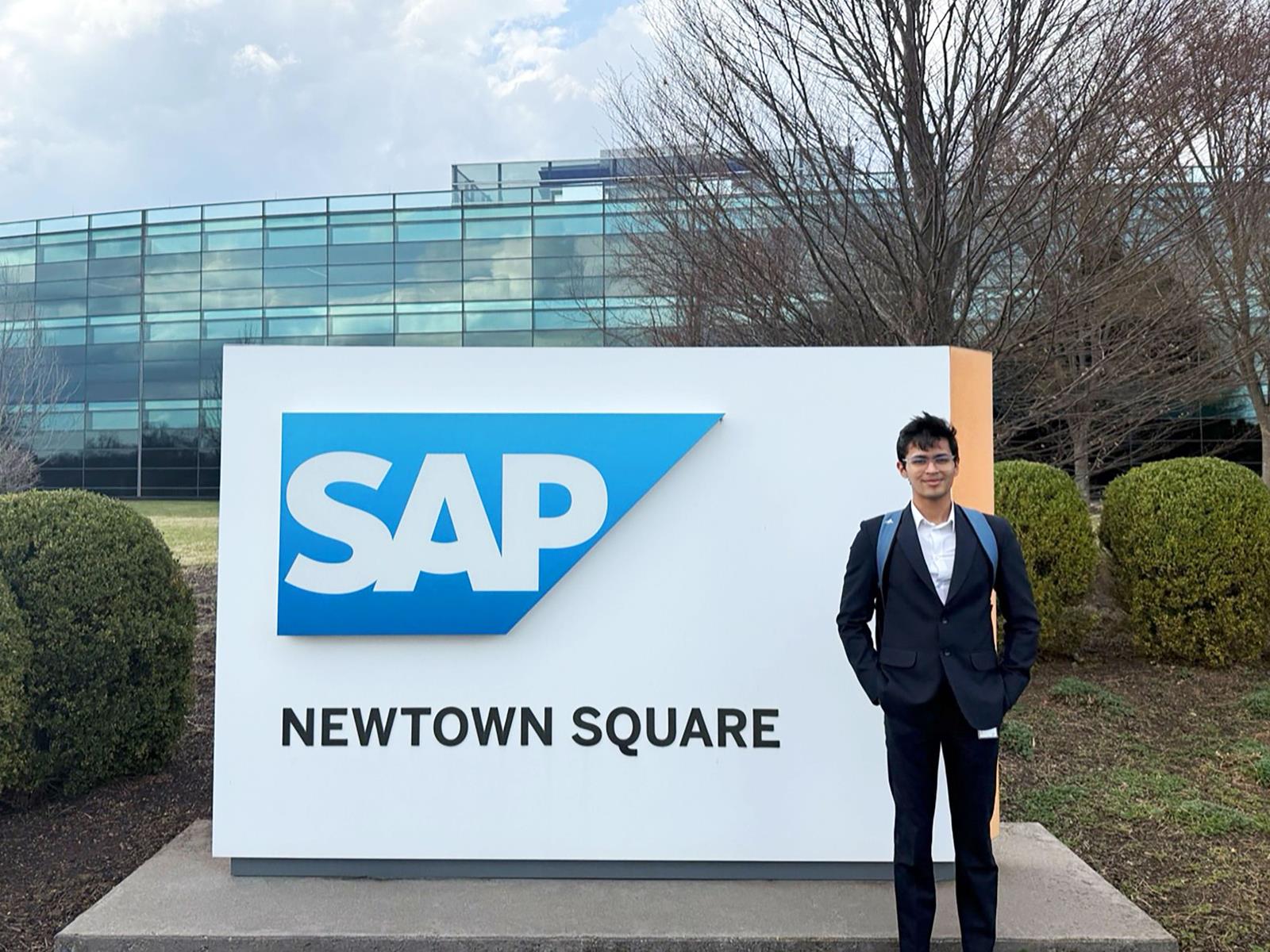 A Drexel student in front of SAP Building signage.