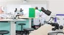 Microscope in a lab with people in lab coats in background