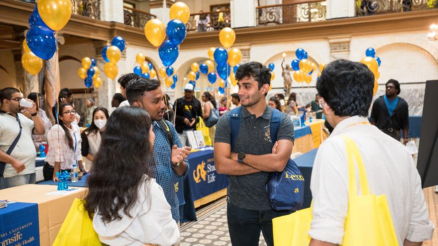 Graduate students at orientation in Main Building with blue and gold balloons