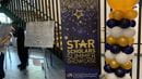 Blue and gold balloons and a sign reading STAR Scholar Summer Showcase in BEntley Hall
