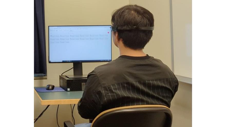Man faces a computer screen wearing an EEG headset