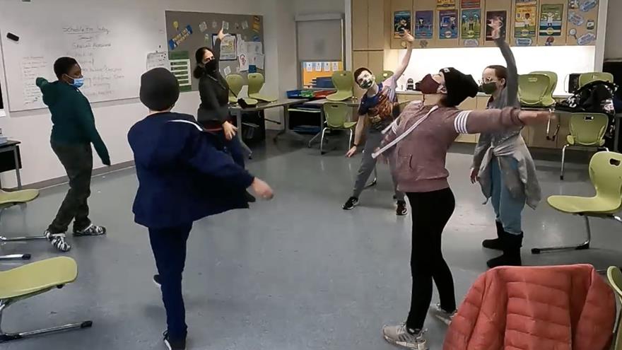 five middle school students and an adult instructor standing in a wide circle dancing