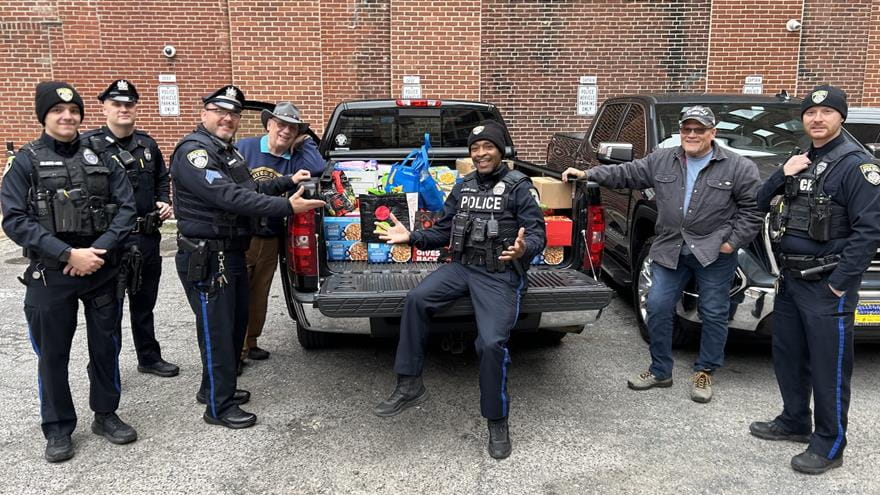 Drexel police officers standing by a black pick-up truck filled with presents.