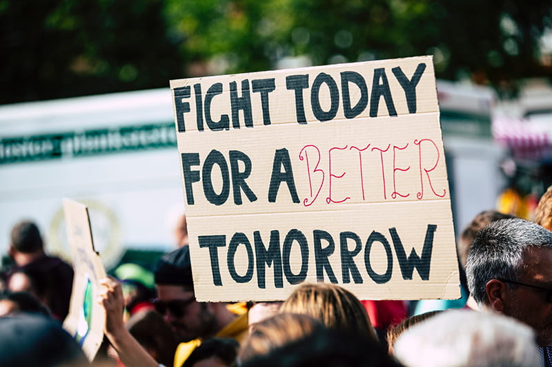 A protest sign reads "Fight today for a better tomorrow."