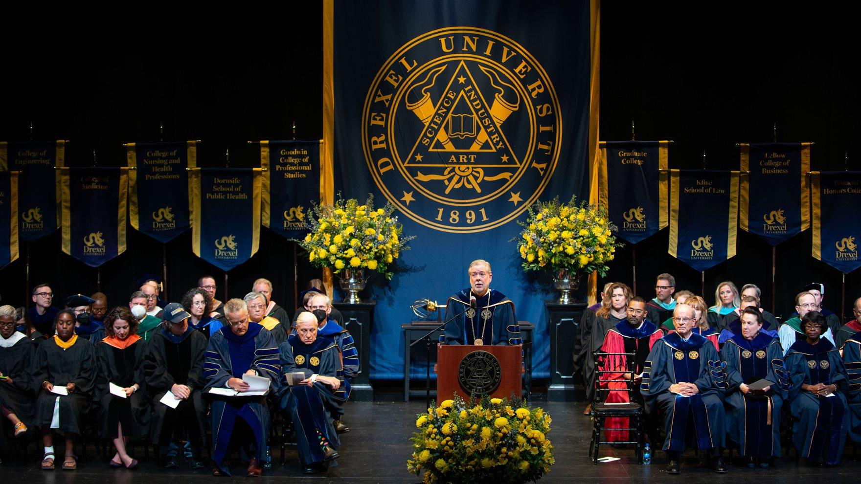 President John Fry stands onstage at Drexel&#39;s 2022 Convocation ceremony. 