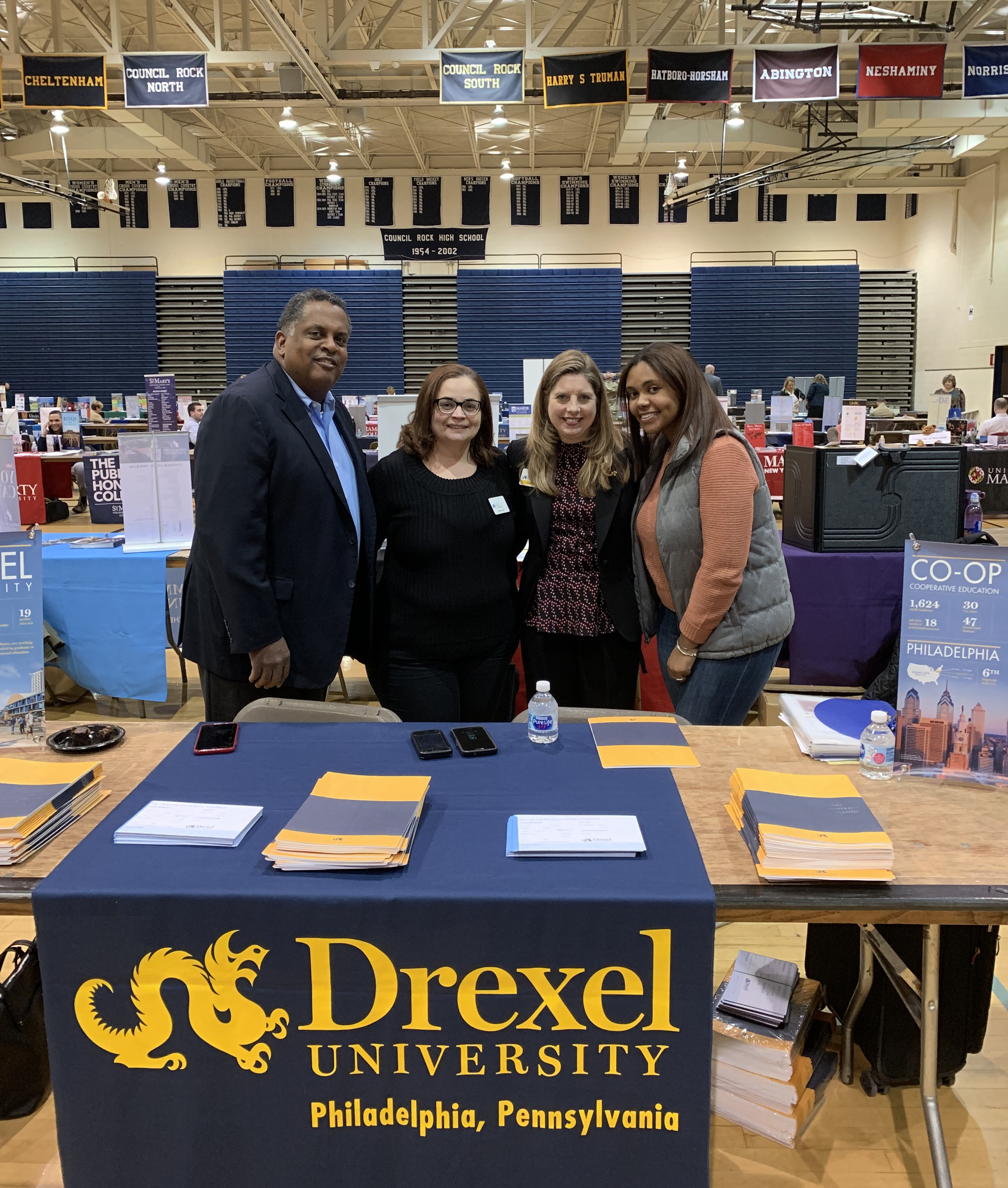 Alumni Ambassadors Carvon Johnson, BS ’85, MS ’88; Izabelle Gómez, BS ’04; Catherine Campbell-Perna, BS ’95, MS ’11; and Janai Johnson, BS ’18 talk to perspective students and their parents at a packed college fair at Council Rock North High School in Bucks County, Pennsylvania. 