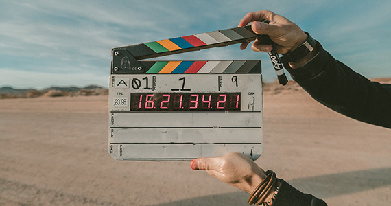 a closeup of a pair of hands holding a clapperboard in the desert