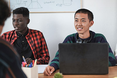 Photo of two students sitting at a table with a laptop