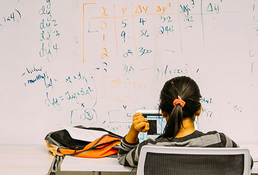 Student studying at a desk in front of a white board 
