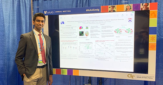 Photo of Drexel student Abishek Jeyapratap standing next to research poster