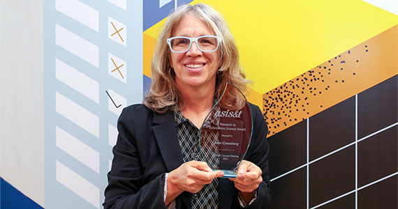 Photo of Jane Greenberg holding ASIST Award trophy in front of mural