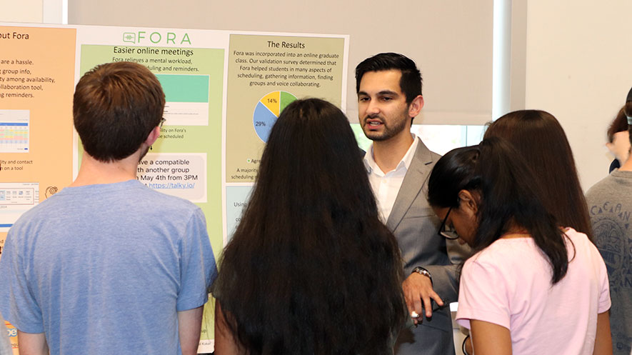 Photo of student presenting Senior Project poster to four people