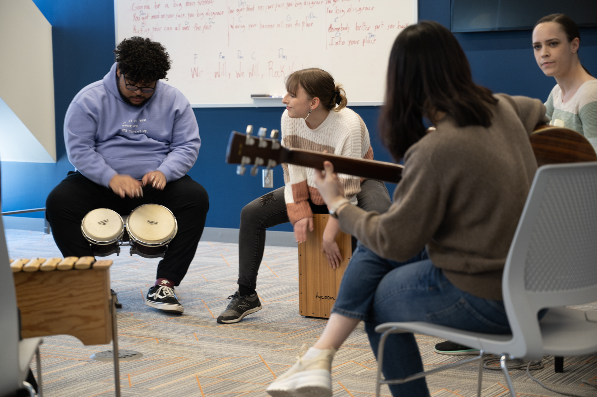 students sit in a circle playing instruments like drum and guitar