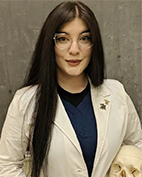 Headshot of Allison Denman with long, dark hair, wearing glasses, holding a skull