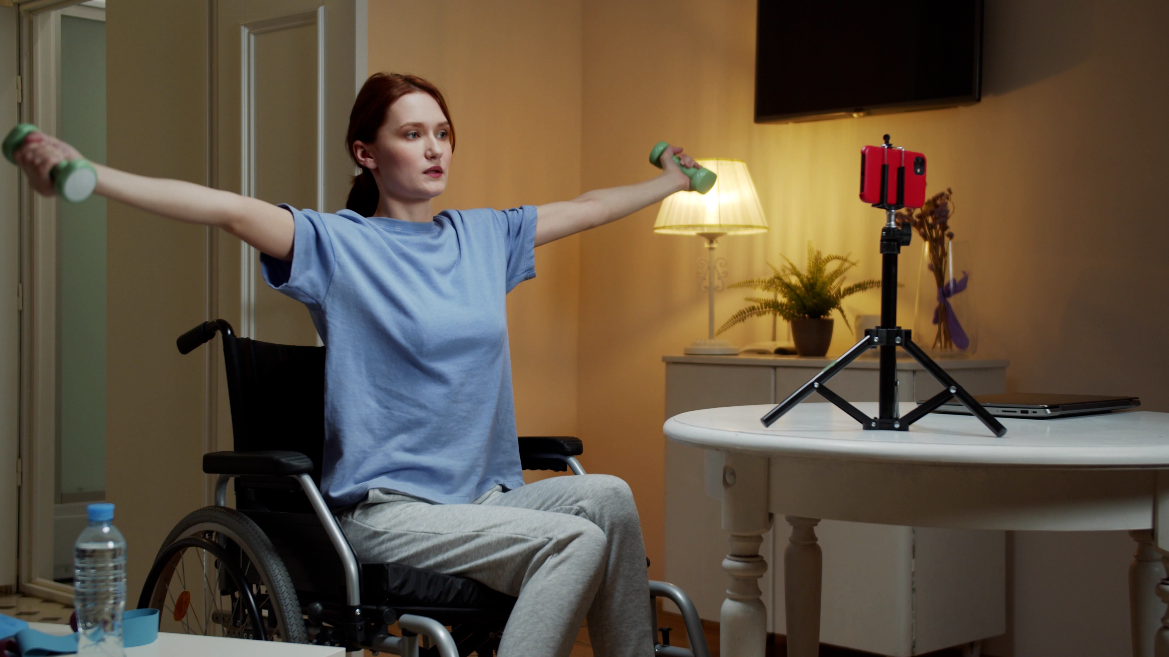 woman sitting in a wheelchair holding weights with extended arms