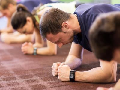 Group of young adults doing exercise planks in a gym.