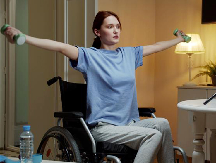 woman in wheelchair holding weights at shoulder height