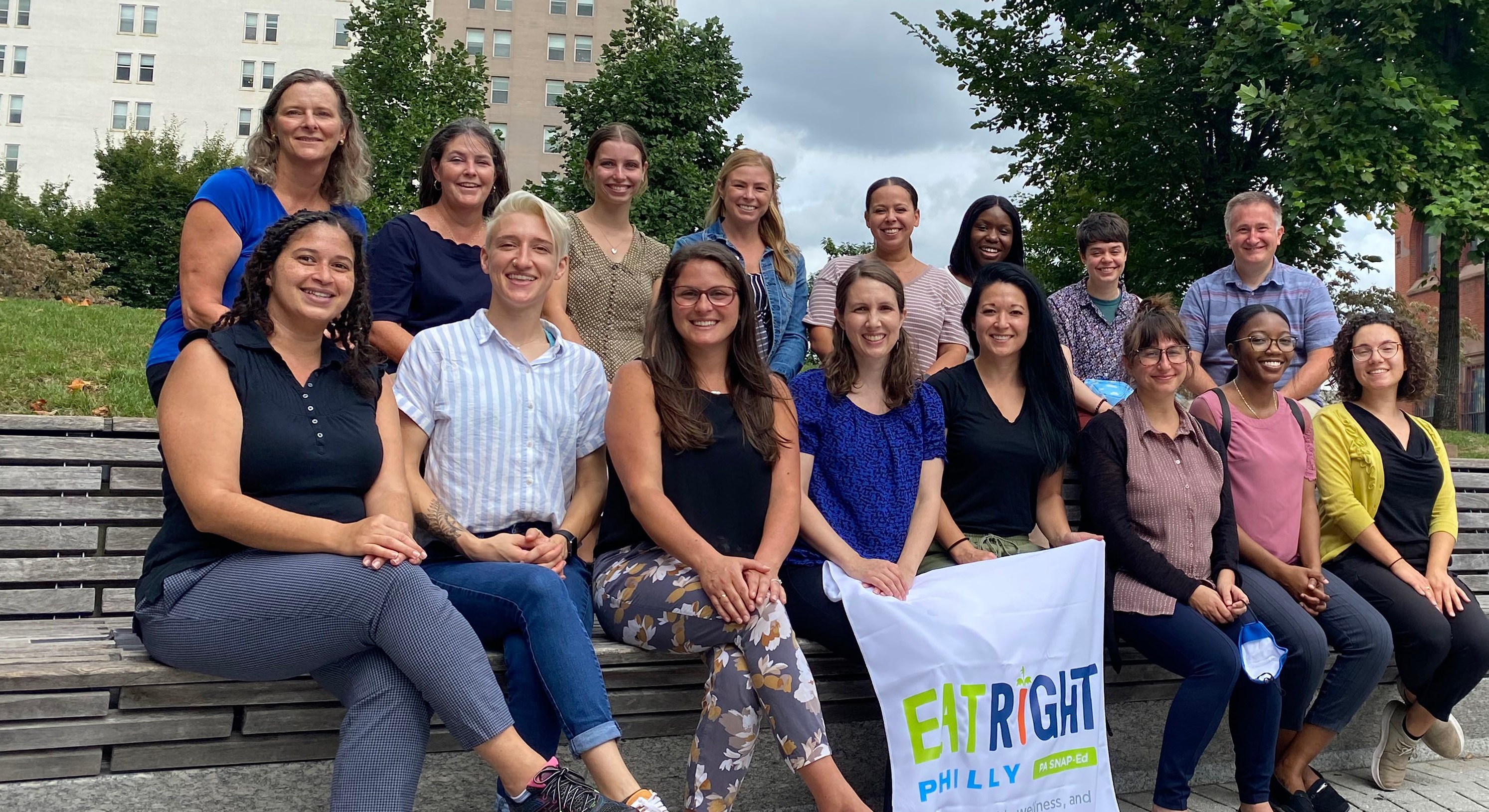 The Eat Right Philly nutrition team sitting as a group outdoors in front of a tree and building.