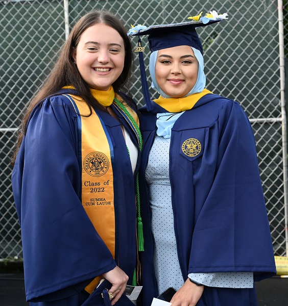 Two females wearing blue and gold caps and gowns