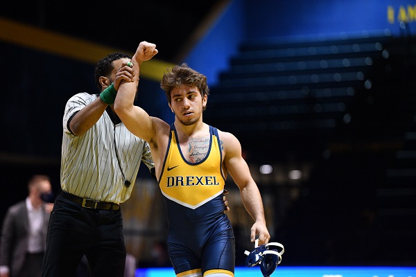 Drexel University wrestler in his uniform with one arm being held in victory by the referee.
