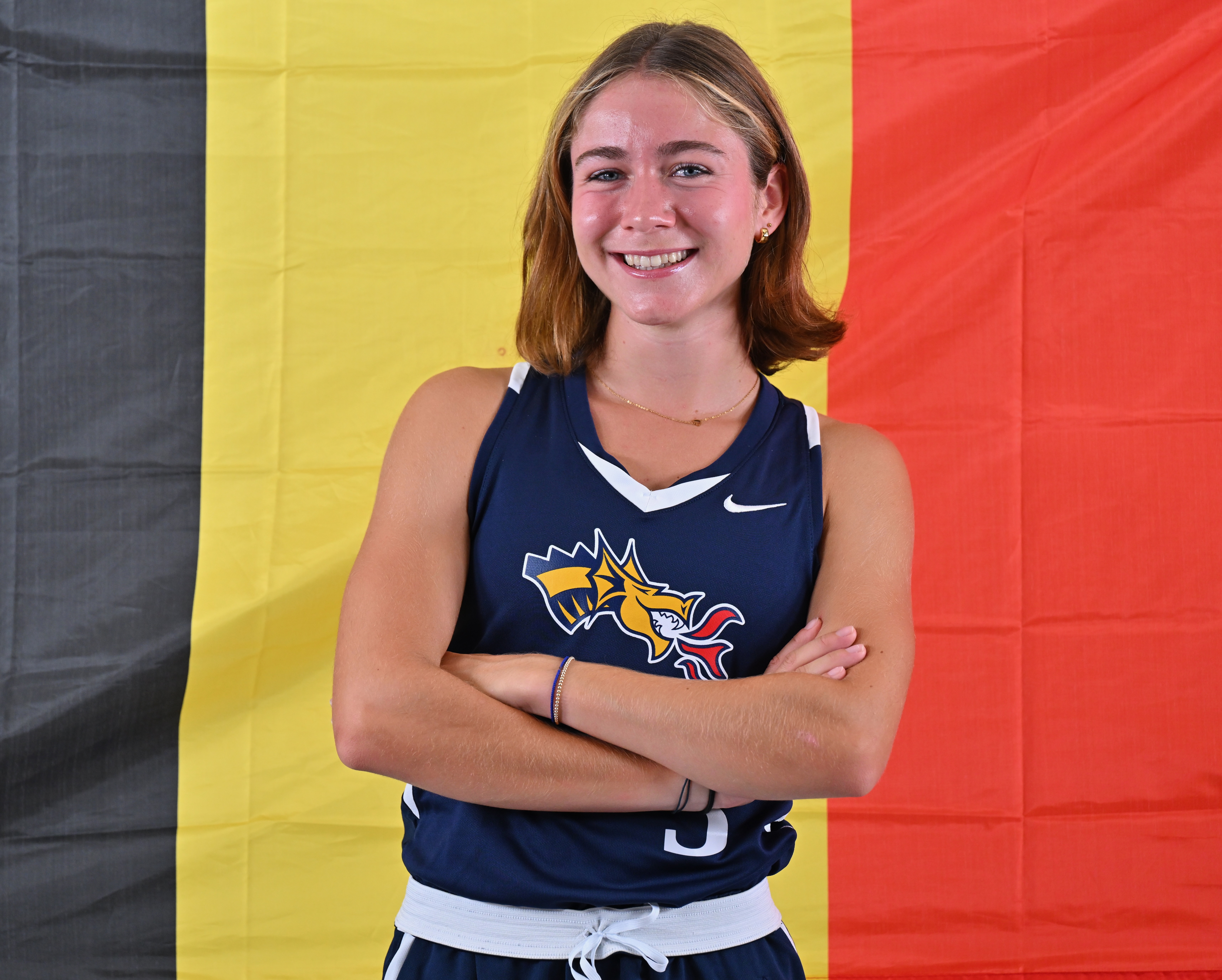 Division I Field Hockey's Valentine Van Hellemont standing in front of Belgian Flag