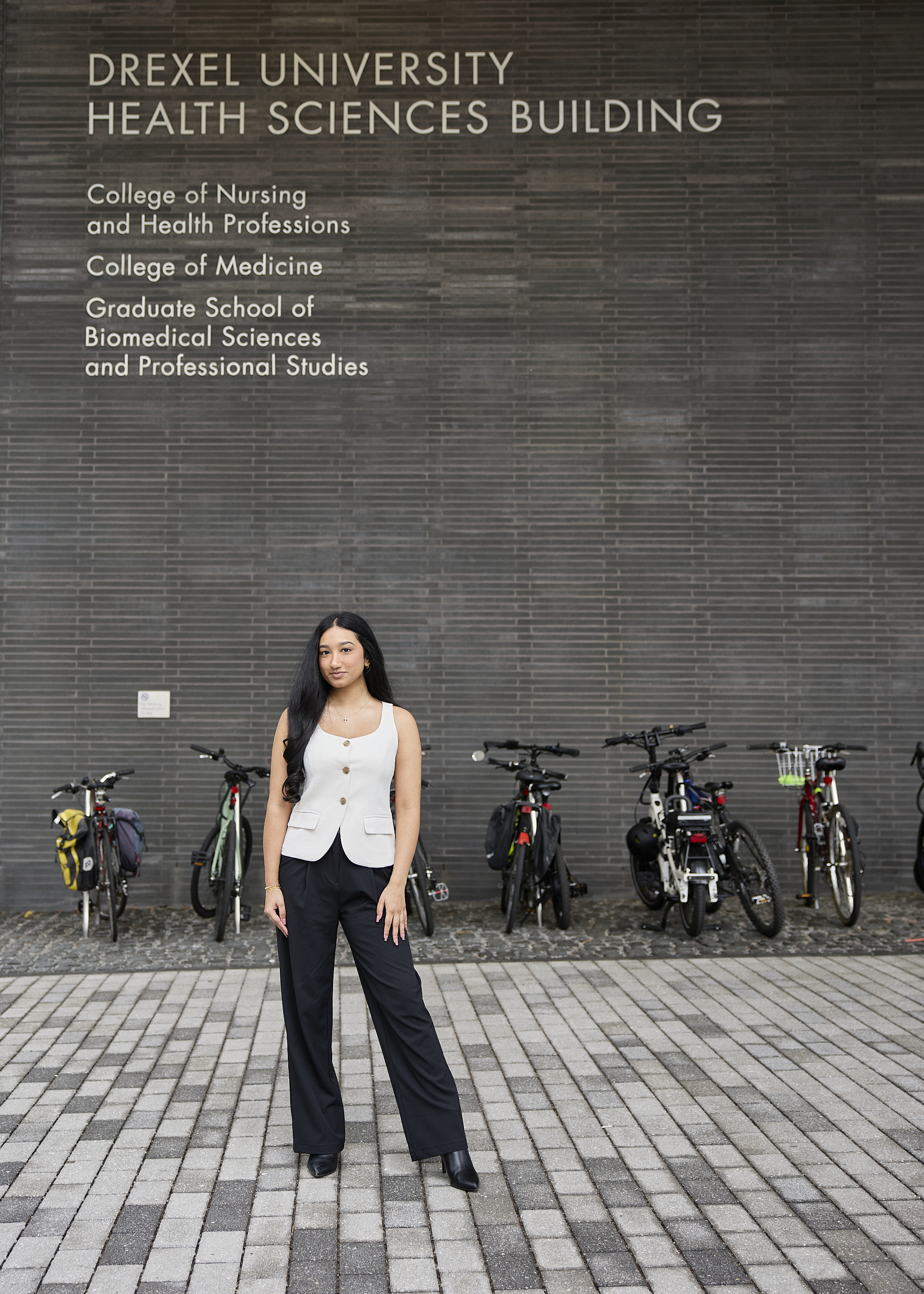 Senior Health Science student Jessica Poovathinkal posing in front of Health Science Building exterior building signage