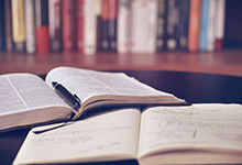 Book and notebook open on a table in a library